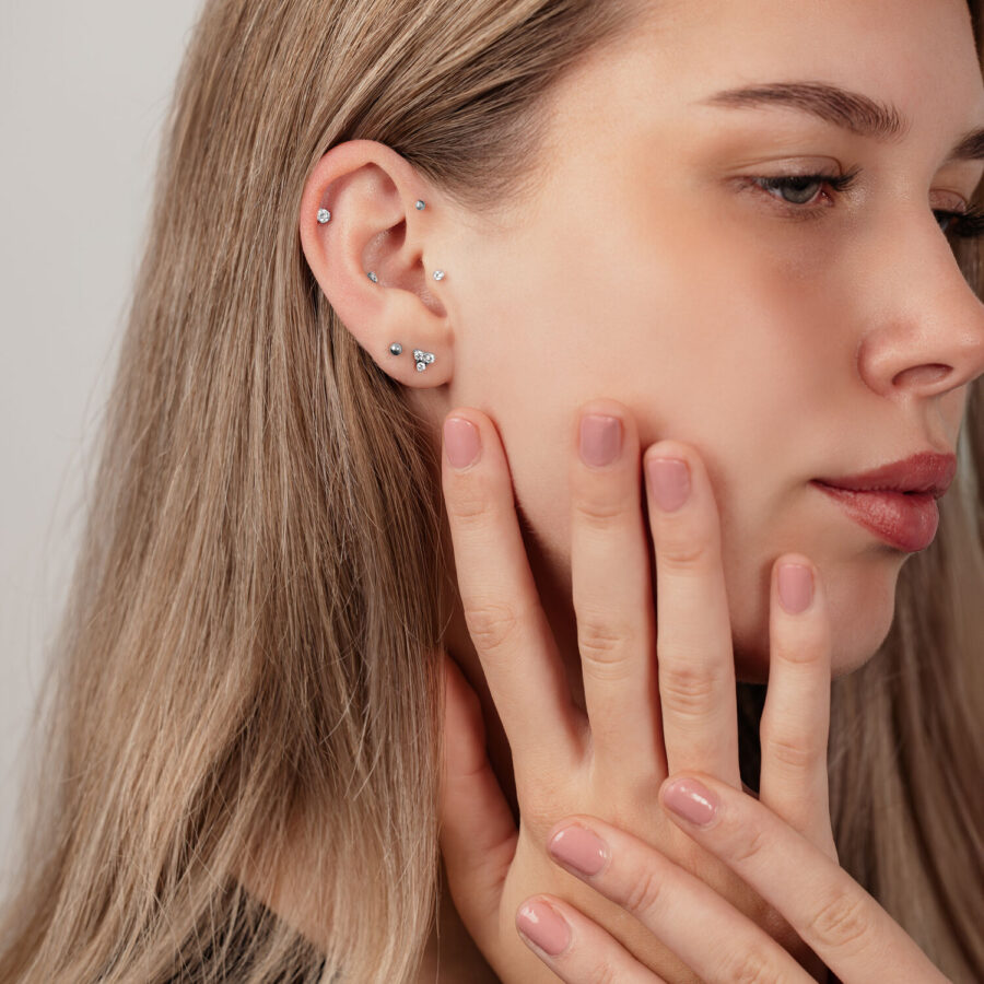 Primer plano de una oreja con bolas de labret de titanio plateadas en varios tamaños