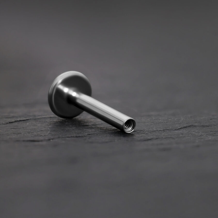 Labret de titanio plateado con rosca interna sobre fondo gris