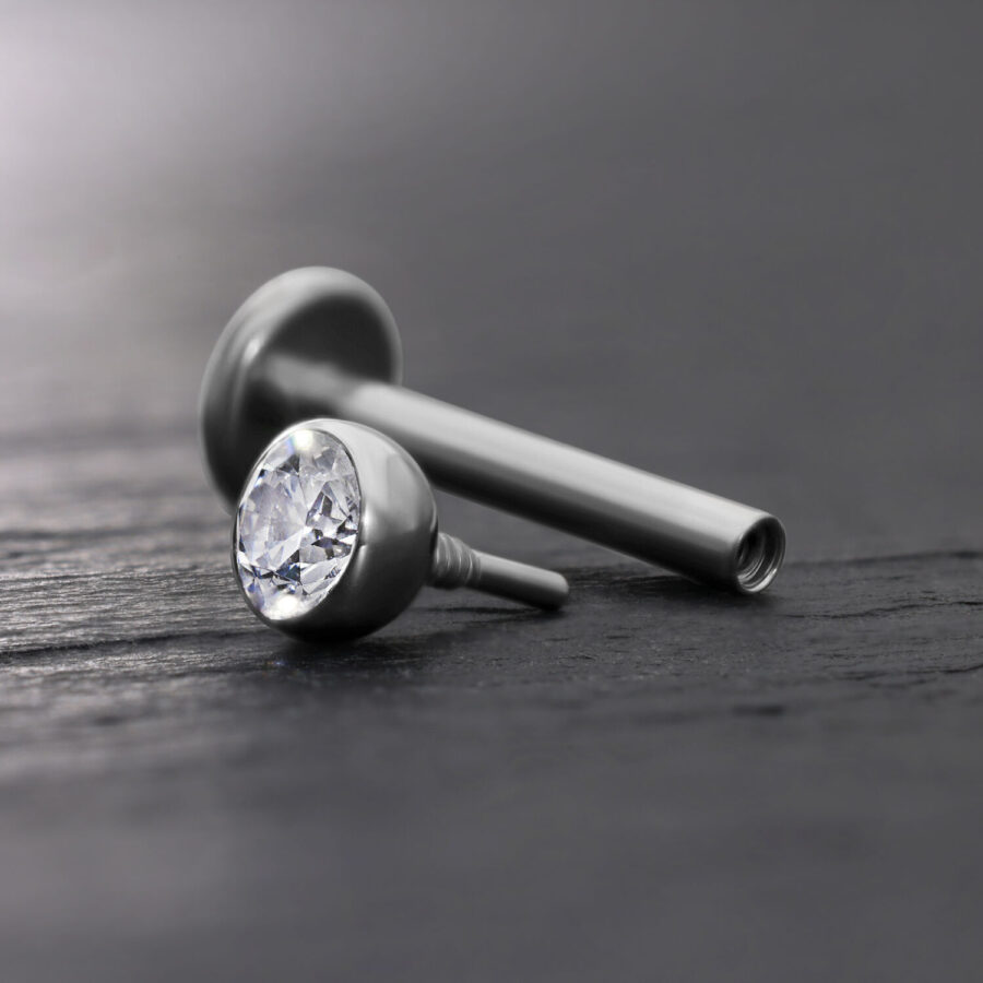Accesorio de labret plateado con bola de cristal clara sobre fondo gris