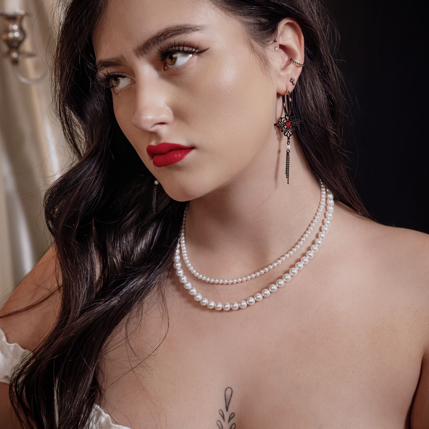 Schwarze Sacred Heart Emaille Hoops Ohrringe Frau mit schwarzen Sacred Heart Emaille Hoops Ohrringen und Perlenkette