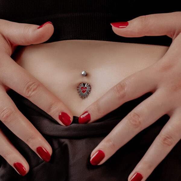 Mujer con esmalte rojo lleva Sacred Heart Bananabell en el ombligo