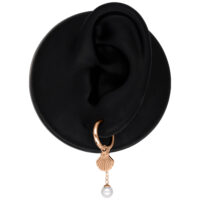 Roségoldene Ohrringe mit Muschel und Perlenanhänger auf schwarzem Hintergrund