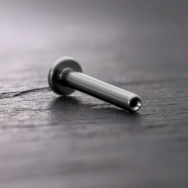 Labret de titanio Push Fit plateado sobre fondo de madera oscura