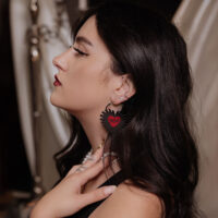 Schwarze Sacred Heart Creolen am Ohr Frau mit langen dunklen Haaren trägt schwarze Sacred Heart Creolen aus Chirurgenstahl