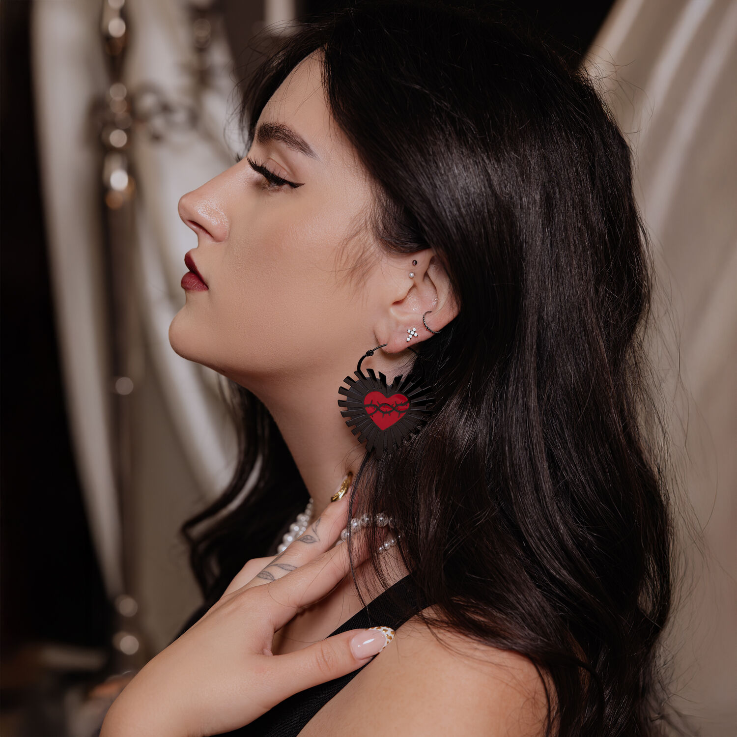 Schwarze Sacred Heart Creolen am Ohr Frau mit langen dunklen Haaren trägt schwarze Sacred Heart Creolen aus Chirurgenstahl