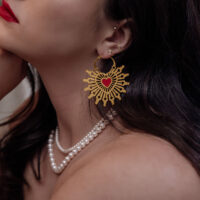Aros de aro dorados con corazón rojo en una mujer