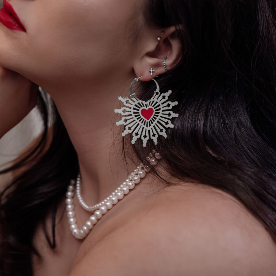 Mujer con pendientes Sacred Heart en plata y negro, primer plano