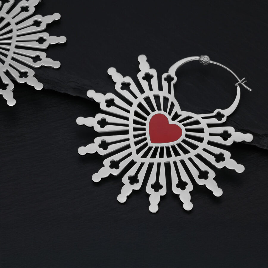 Aros plateados en forma de corazón con corazón rojo sobre fondo oscuro