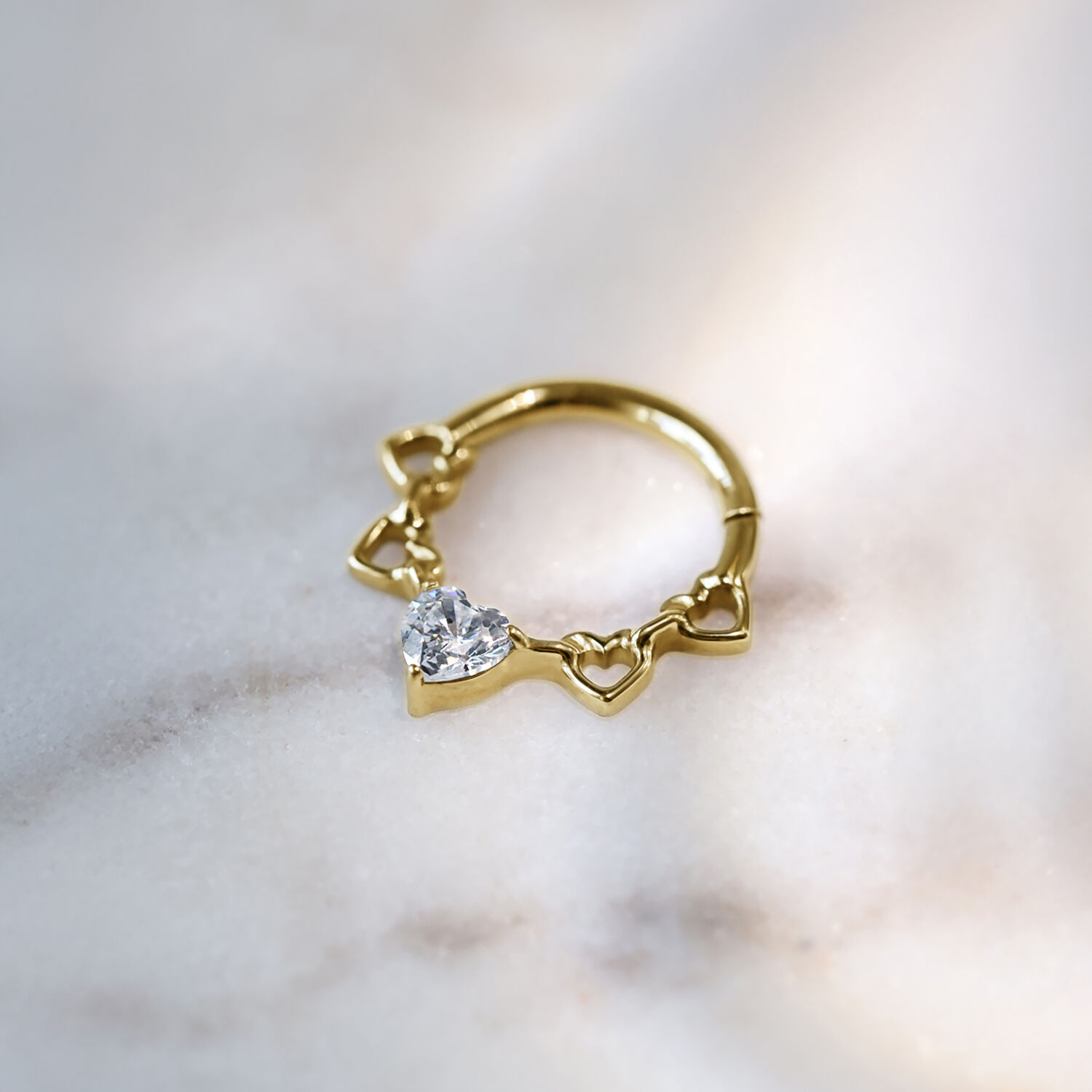 Clicker de Septum de Corazones de Cristal Dorado Clicker de septum dorado con diseño de corazón y cristal sobre fondo claro