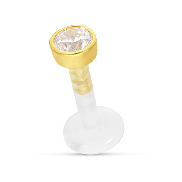 Labret con montura dorada y cristal claro sobre fondo blanco