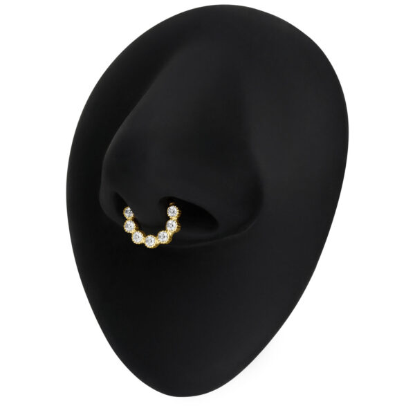 Anillo de piercing septum dorado con cristales de moissanita sobre fondo negro