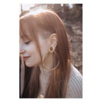 Roségoldene Hollowed Hoops im Ohr getragen Frau mit langen Haaren trägt große roségoldene Hollowed Hoops im Ohr