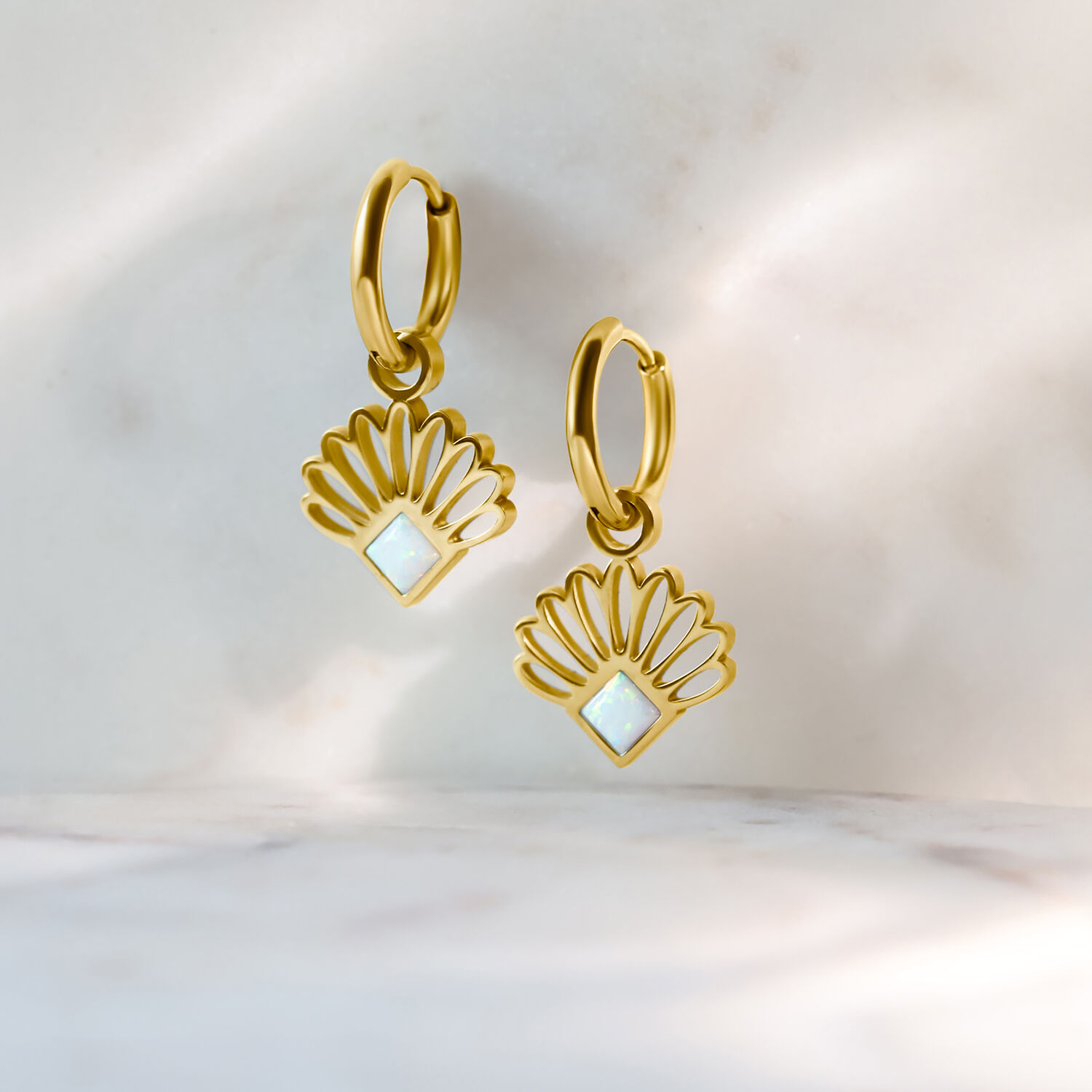 Aros de abanico de ópalo dorado de acero quirúrgico Dos aros dorados con diseño de abanico opalino sobre fondo claro