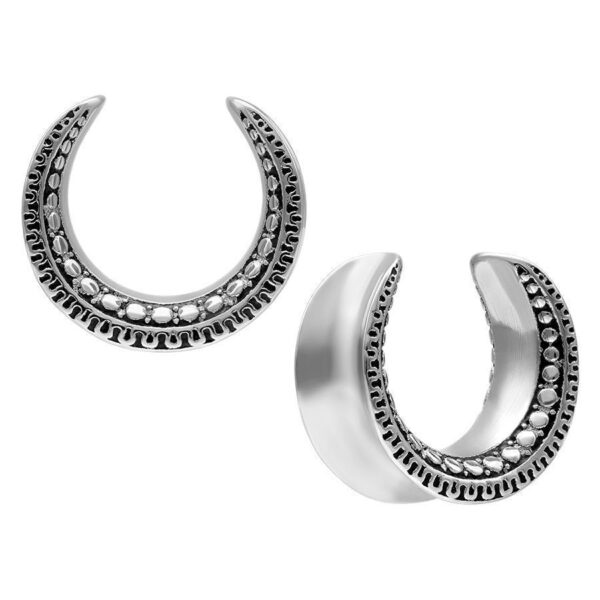 Dos Ear Saddles plateados con diseño maorí sobre fondo blanco