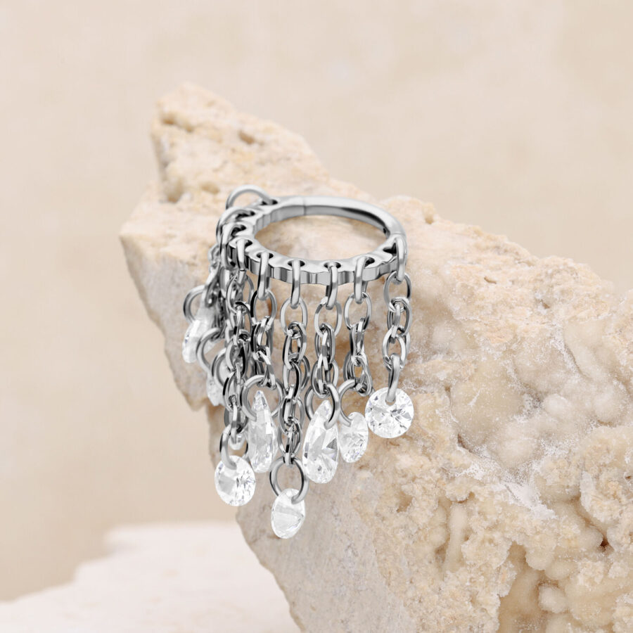 Anillo de piercing plateado con cristales claros sobre piedra clara