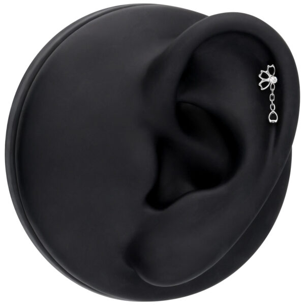 Accesorio de piercing de oreja plateado con cristal sobre fondo negro