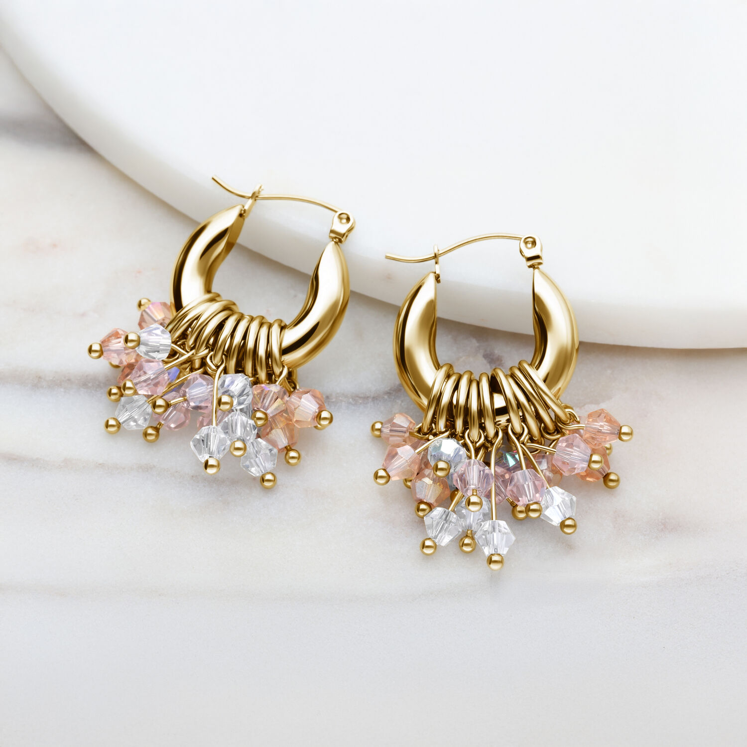 Pendientes de aro dorados con colgantes de cristal de colores sobre fondo blanco