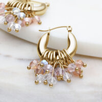 Glamour Hoops pendientes dorados con cristales de colores sobre fondo claro