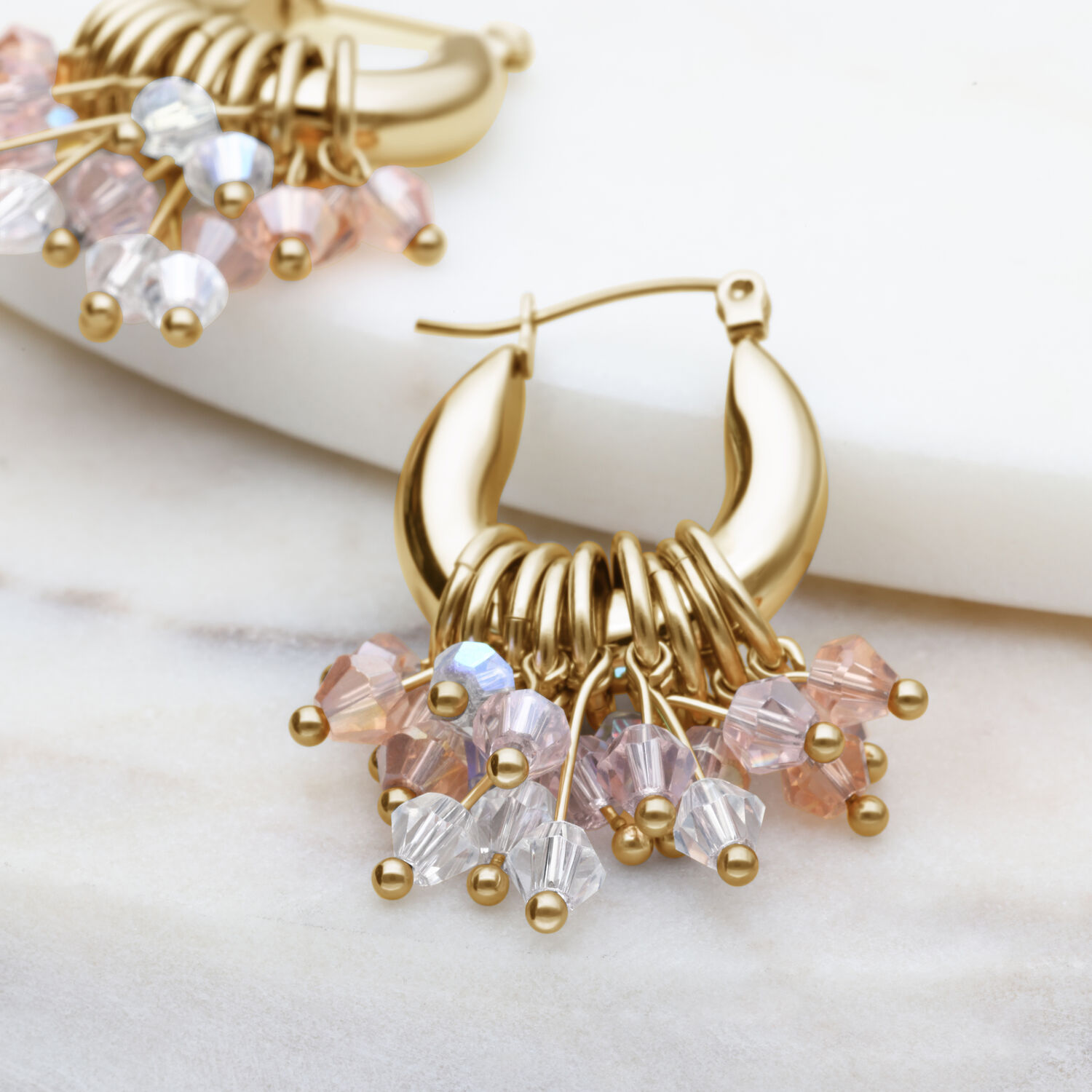 Glamour Hoops pendientes dorados con cristales de colores sobre fondo claro