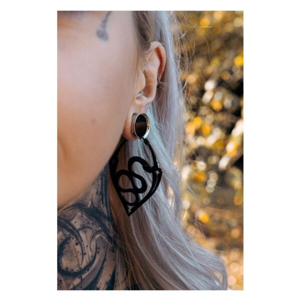Primer plano de una oreja con aros Snake negros, fondo desenfocado