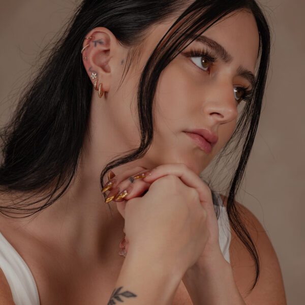 Mujer con aro de flor de 14K Gold con Moissanite en la oreja, fondo discreto
