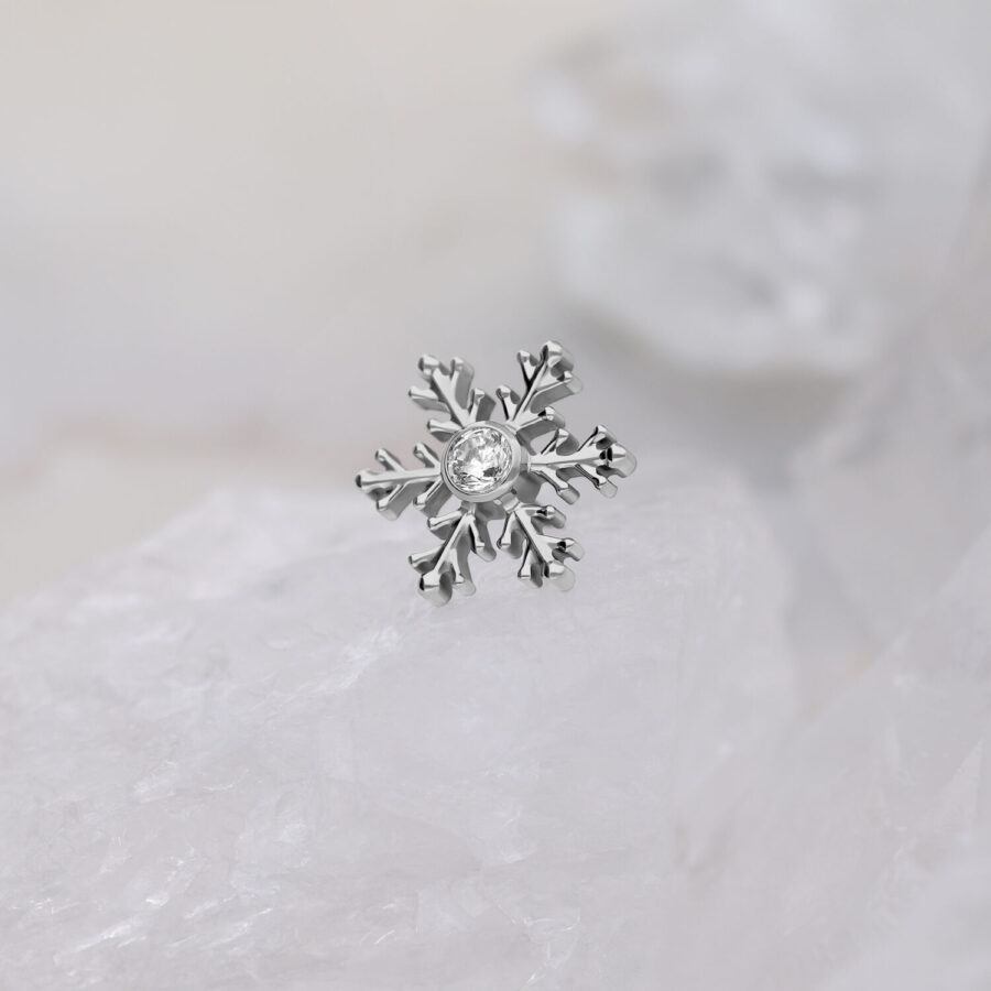 Adorno de piercing de copo de nieve plateado con cristal claro sobre fondo blanco