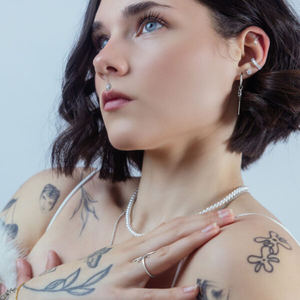 Mujer con varios piercings, cristal en la oreja, look elegante