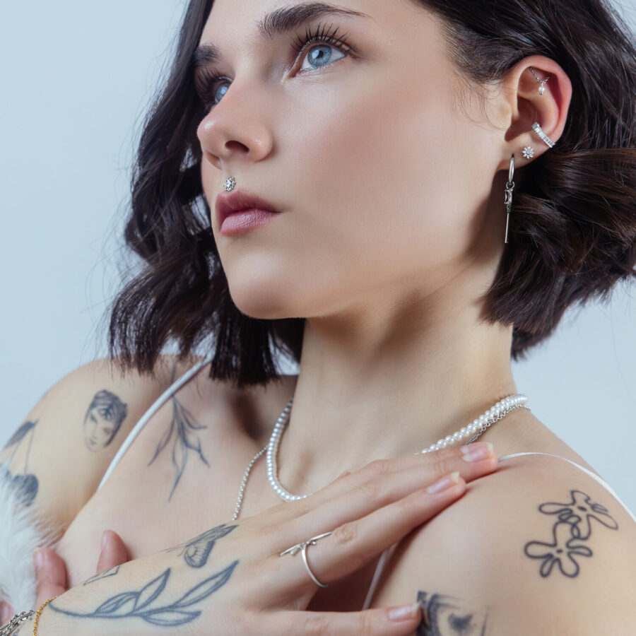 Mujer con varios piercings, cristal en la oreja, look elegante