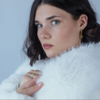 Wildcat Dorado Helix Push Fit Adorno Mujer con adorno dorado Helix Push Fit en la oreja y abrigo de piel blanca