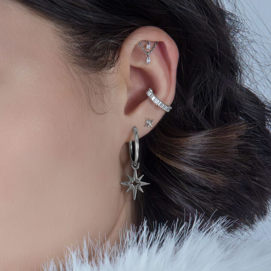 Helix de plata con cristales en una oreja, fondo oscuro