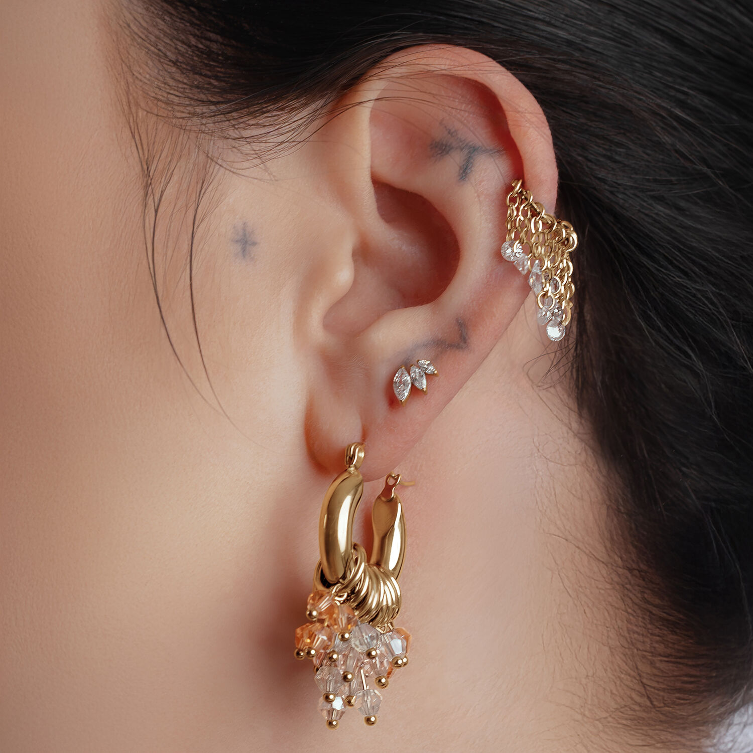 Pendientes Glamour Hoops dorados en la oreja de una persona con más piercings