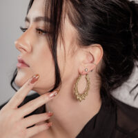 Pendientes de girasol dorados en perfil Mujer con pendientes de girasol dorados, perfil lateral, cabello negro