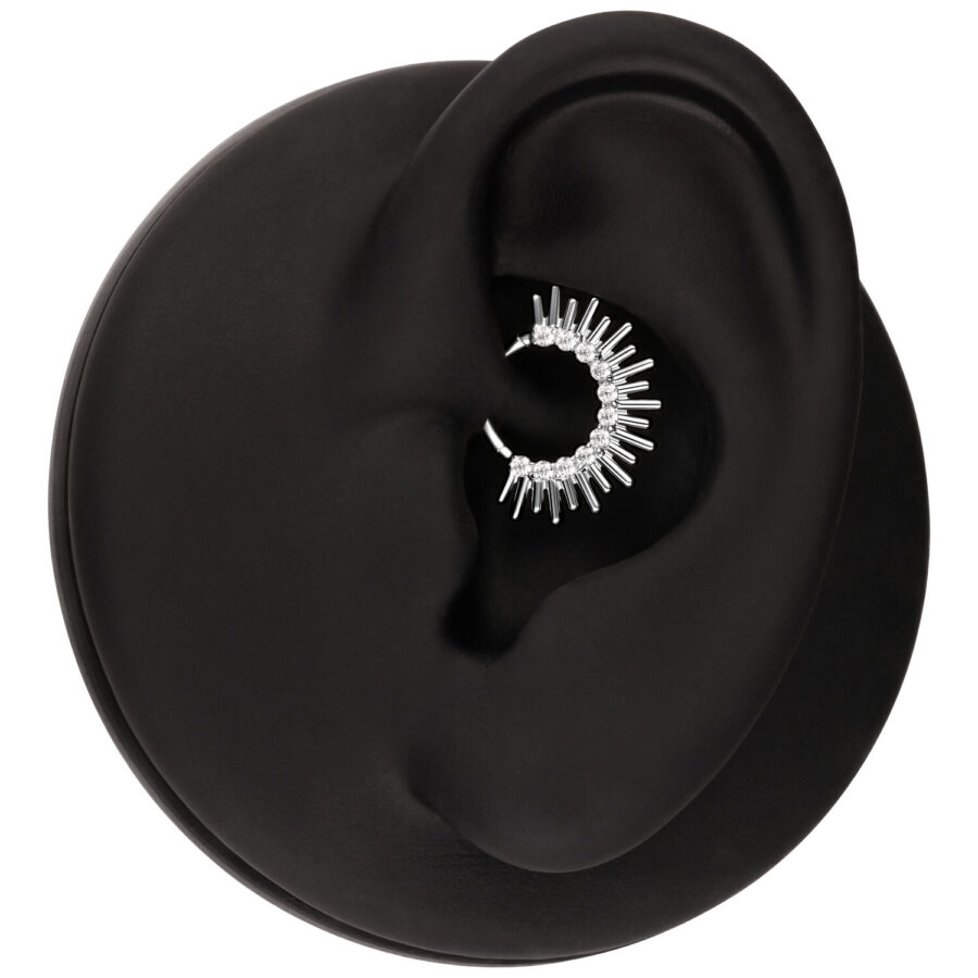 Clicker de septum plateado en forma de rayos de sol en una oreja negra sobre fondo blanco