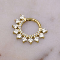 Clicker de septum dorado con adorno de cristal sobre fondo de mármol