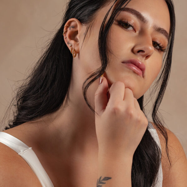 Mujer con accesorio de 14K Gold con Moissanite en la oreja sobre fondo neutro