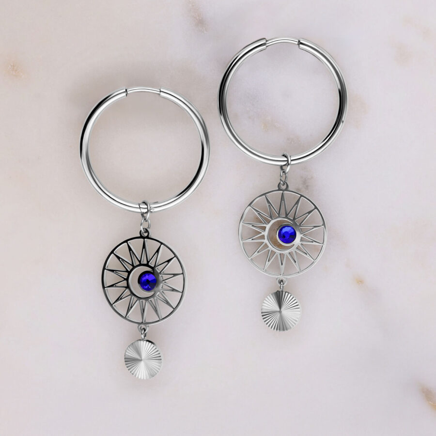 Aros plateados con cristal azul oscuro sobre fondo gris claro