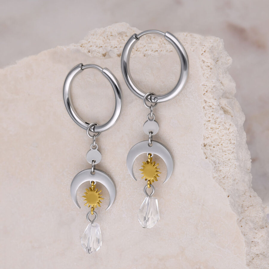 Aros de plata con colgantes de soles dorados y cristales claros sobre fondo claro