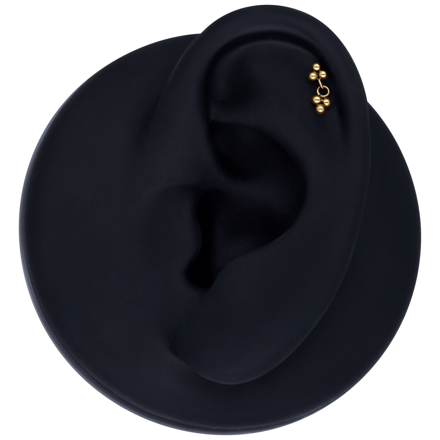 Ajuste de piercing dorado en un modelo de oreja negra sobre fondo blanco