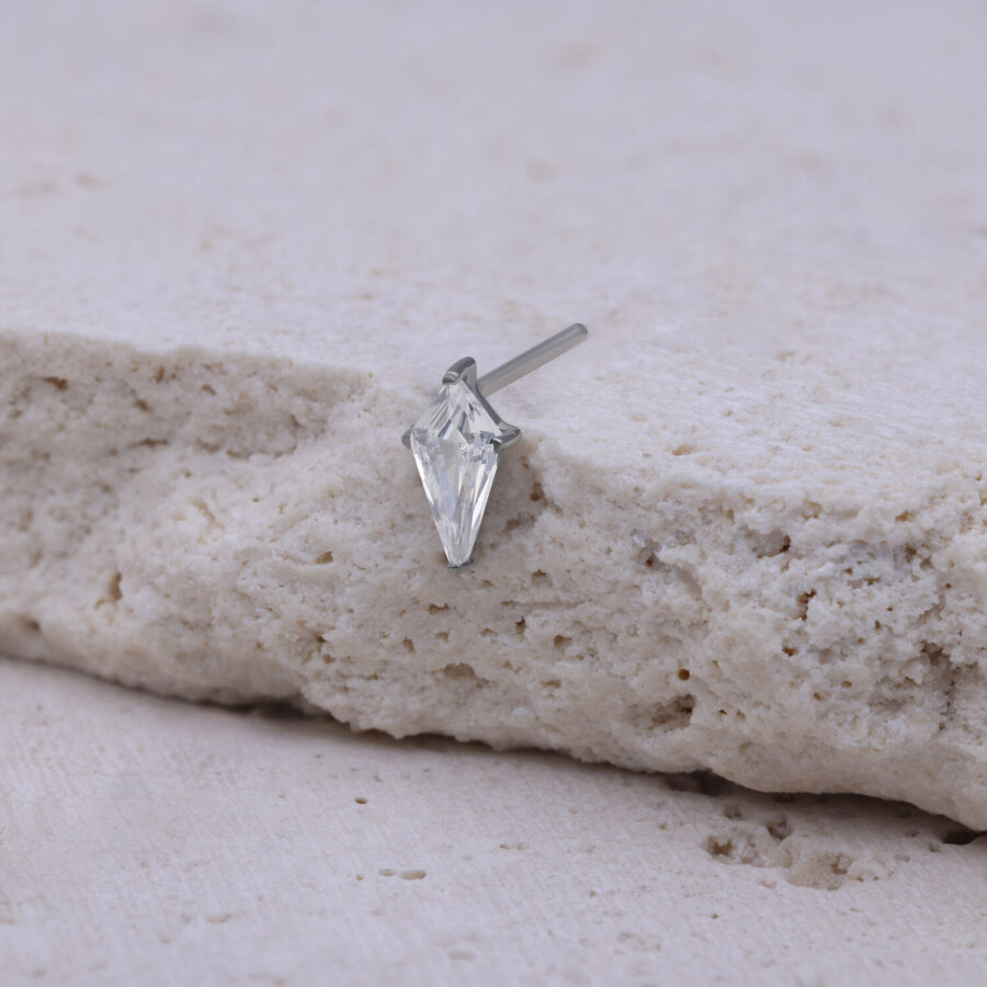 Adorno Push Fit plateado con piedra cristalina sobre fondo beige