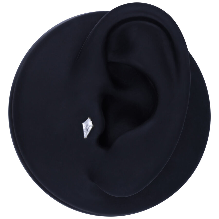 Accesorio de cristal plateado en forma de triángulo sobre una oreja modelo negra