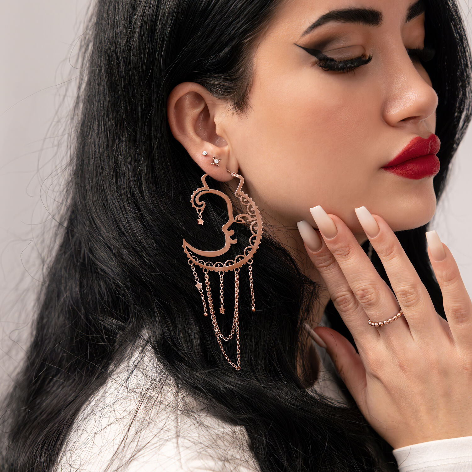 Frau mit Roségold-Ohrringen im Sun Moon Design vor neutralem Hintergrund