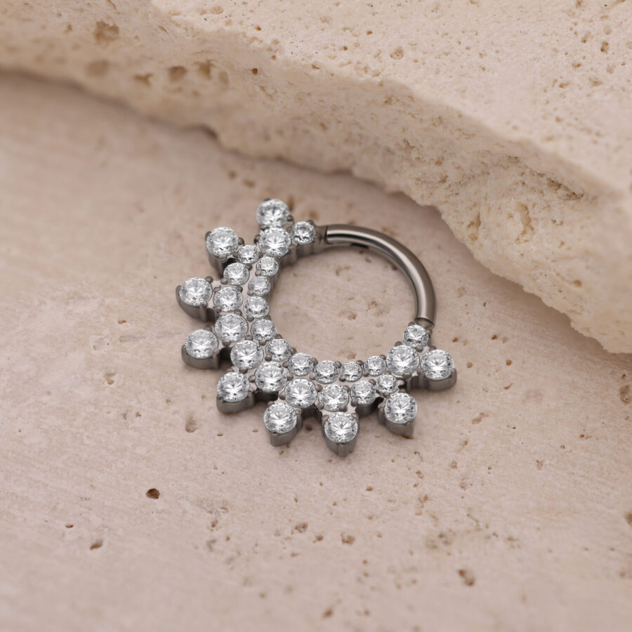 Clicker de septum plateado con cristales brillantes sobre fondo beige