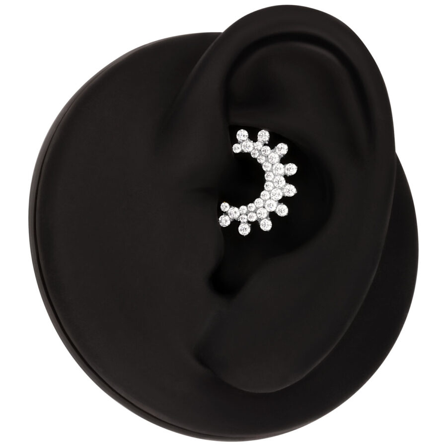 Clicker de septum plateado con cristales brillantes, presentado sobre fondo negro