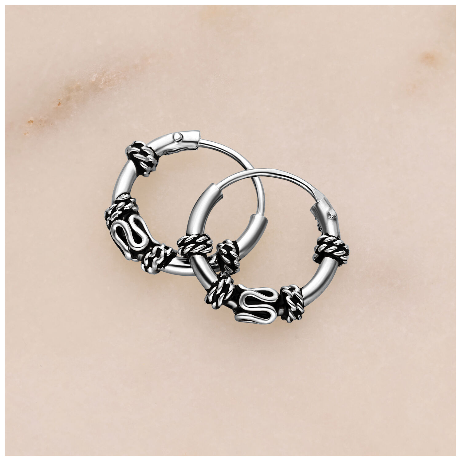 Aros de plata con detalles de nudo sobre fondo claro