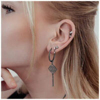 Pendientes Clover Hoops negros de acero quirúrgico en la oreja de una mujer