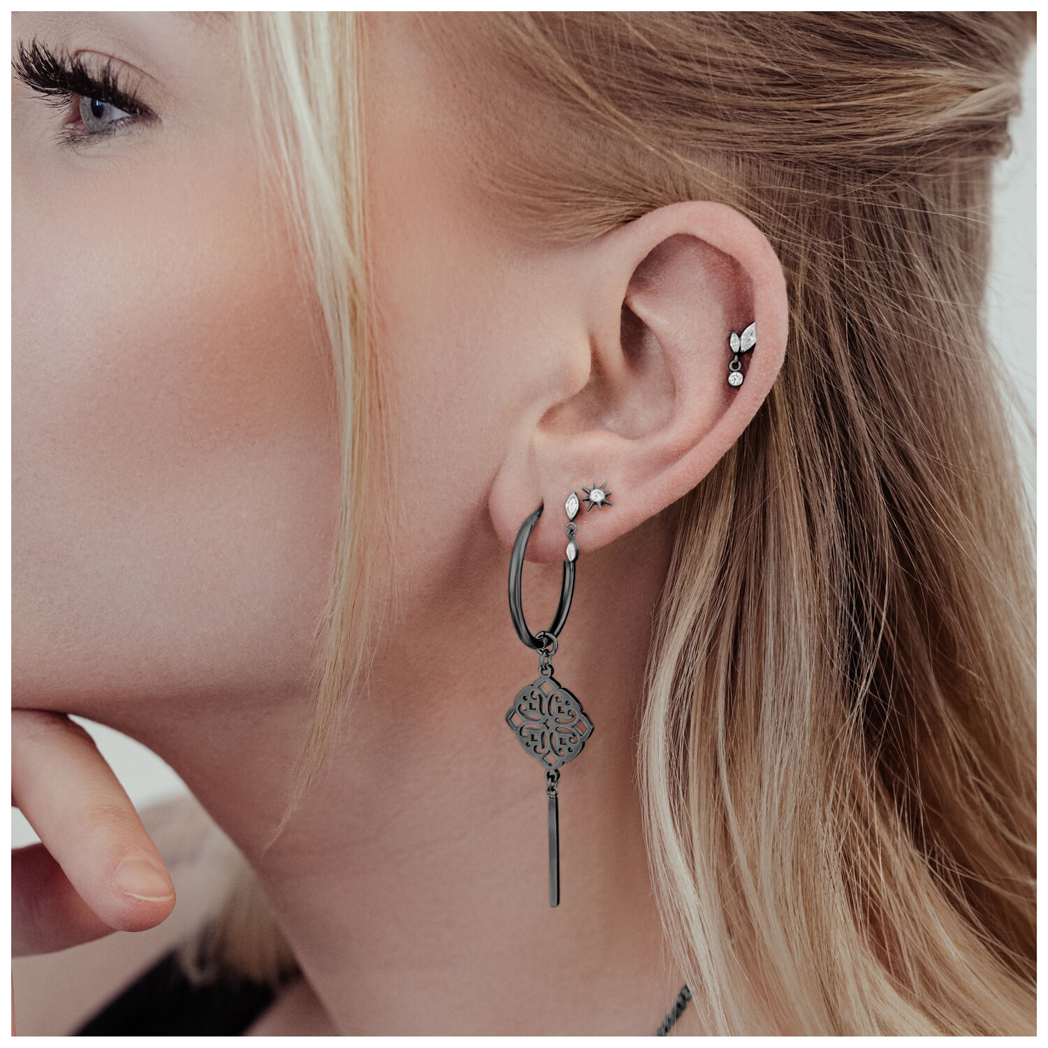 Pendientes Clover Hoops negros de acero quirúrgico en la oreja de una mujer