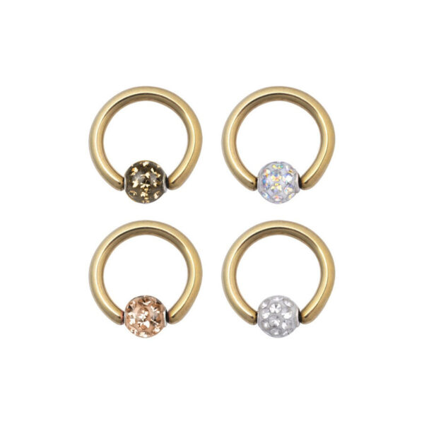 Cuatro anillos de clip dorados con cristales de diferentes colores sobre fondo blanco