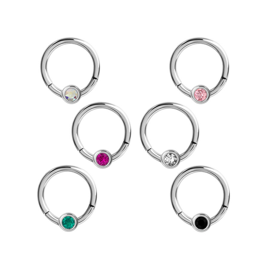 Cinco clickers de septum plateados con cristales de varios colores sobre fondo blanco