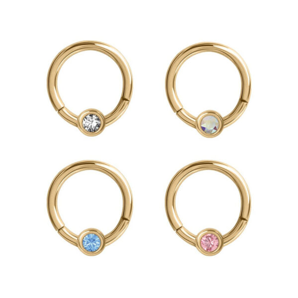 Cuatro anillos de piercing dorados con cristales claros, azules, rosas y brillantes sobre fondo blanco