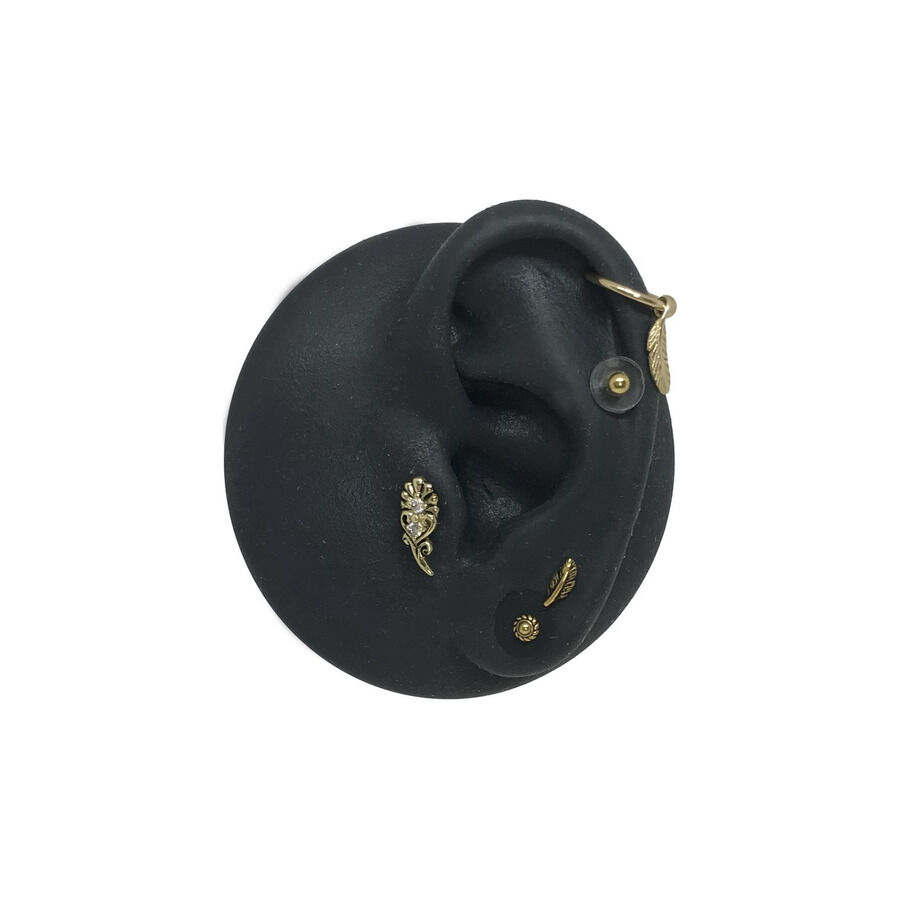 Disco de silicona para piercing con apliques dorados Modelo de oreja de silicona negra con apliques dorados para piercing sobre fondo blanco